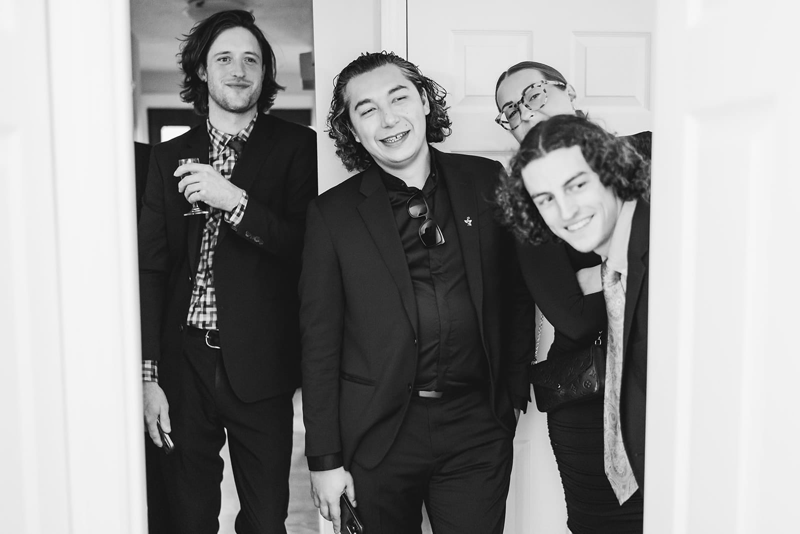 A documentary photograph of guests watching a bride shaving a groom's head before cancer treatment during a in home celebration after their intimate Worcester Art Museum Wedding ceremony
