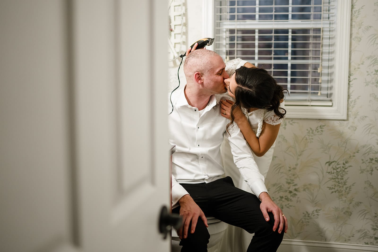 A documentary photograph of a bride shaving a groom's head before cancer treatment during a in home celebration after their intimate Worcester Art Museum Wedding ceremony
